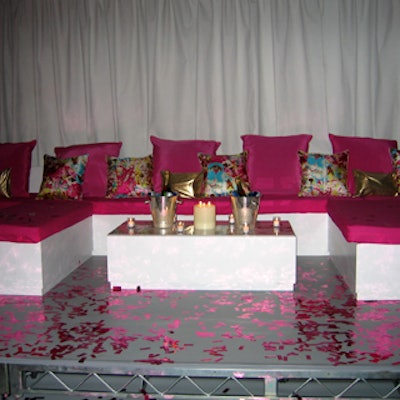 White banquettes and chaise lounges covered with bright fuchsia cushions printed pillows lined the walls. Strips of metallic pink confetti covered the floor and the white cocktail tables.