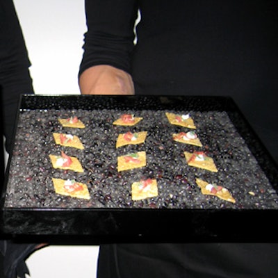 Taste caterwaiters passed hors d’oeuvres from black lacquer trays filled with colored gravel.