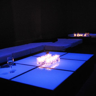 Underlit glass cocktail tables gave off a violet-colored glow, and were topped with cube-shaped, clear glass candle holders with white candles.