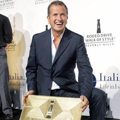 Honoree Mario Testino posed with his award on the red carpet.