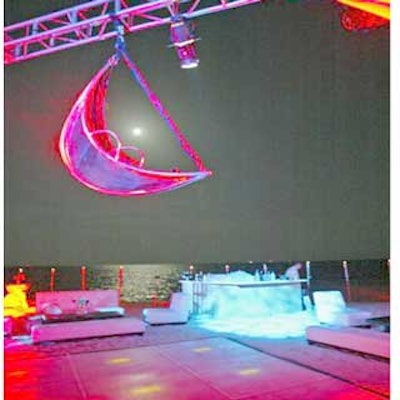 A lit dance floor under a moon-shaped prop suspended from trussing served as the central gathering area for guests at the Nasdaq 100 Open players party.