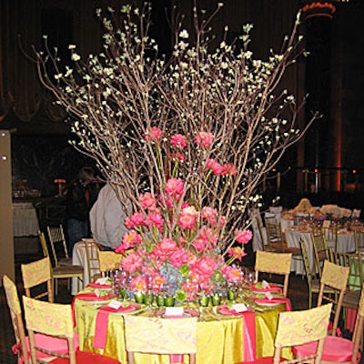 David Beahm mixed shades of pink and green, with pink peonies, moss, and blue hydrangea anchoring the base of large dogwood branches over a table decorated with green votive candles and salmon-colored napkins draped off of plates rimmed in gold and pink. Matching seat cushions and pattern chair covers completed the look.