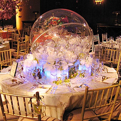 Flora New York's table had a futuristic and ethereal design with globes and glowing blue lights. Dominating the table was a large Lucite globe filled with lime green cymbidium, white cattleya orchids, and stephanotis. Hanging off the chairs were small globes, each with a cymbidium blossom inside for guests to take home.