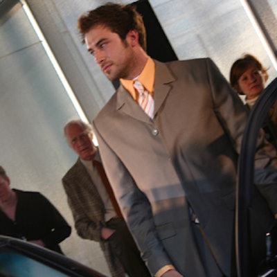 A model stood beside the sedan just before he tore away his suit and revealed a designer racing uniform.