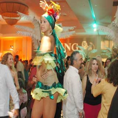 Hot Jam Entertainment dancers in Tropicana-style showgirl costumes performed on platforms among the domino tables at the Amigos for Kids' celebrity domino night at Parrot Jungle.