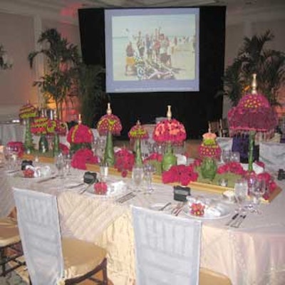 EventSource International adorned tables with ornate centerpieces of deep red roses and long rows of lamps made from red and green flowers and red beads.