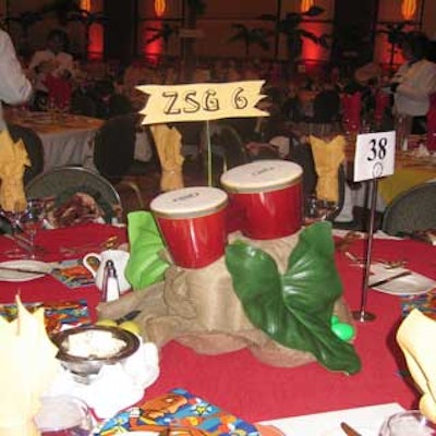 Centerpieces consisted of red conga drums atop a base covered with canvas and arranged against green foliage.