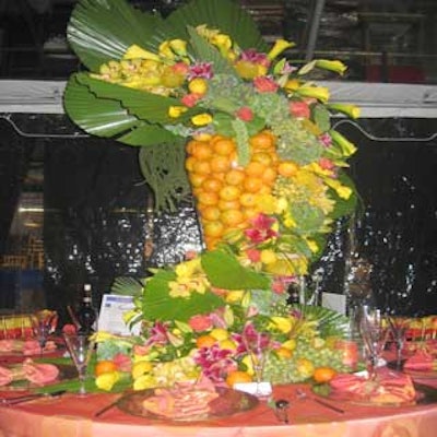 A towering centerpiece of tropical flowers and oranges complemented the mango- and papaya-colored linens of Touch Catering's Latin-style table.
