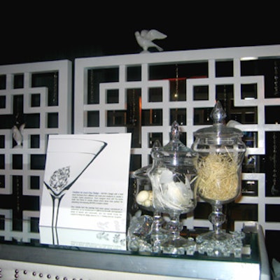 Laura Day’s martini bar featured a white wood backdrop decorated with faux diamond teardrops and white ceramic doves, and a crystal bartop ornamented with diamonds and feathers. The body of the bar was covered with white leather with silver studs.