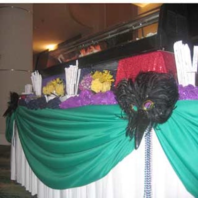 Fabulous Linen draped the food stations with emerald green fabric and added beads, masks, and other Mardi Gras-inspired accents.