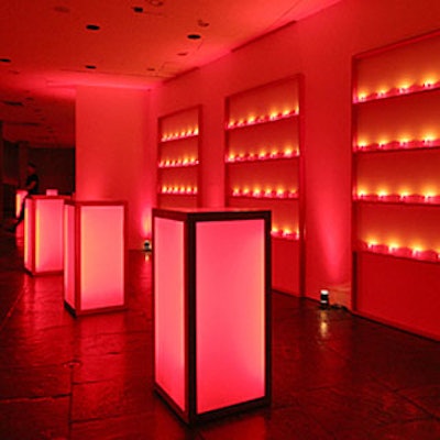 In the cocktail party space, red votive candles lined narrow shelves along the walls and tallboy cocktail tables glowed with red light from within.