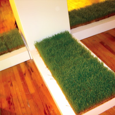 Flats of green grass sat on the hardwood floor at the base of the white pillars in the venue.