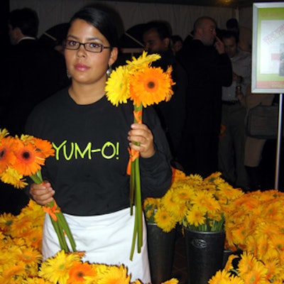 An event staffer handed guests bouquets of yellow and orange gerbera daisies tied together with orange ribbon.