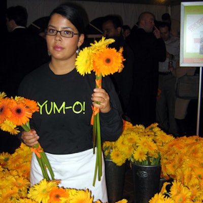 An event staffer handed guests bouquets of yellow and orange gerbera daisies tied together with orange ribbon.