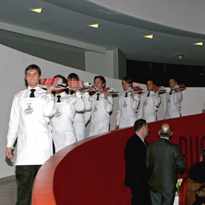 A single-file line of T&L Events caterwaiters dressed in white shirts, black ties and pants, and white aprons printed with the Michelin logo walked down the Guggenheim’s spiraling ramp to deliver stacks of the guide on silver trays at the launch of the Michelin Guide to New York City.