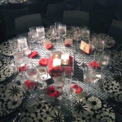 The centers of tables featured groups of cube candles and a scattering of red gerbera daisy heads over playful zigzag-patterned linen.