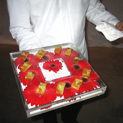 Olivier Cheng Catering and Events served hors d’oeuvres during the cocktail hour on clear trays laden with red gerbera daisy blossoms.