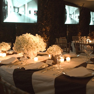 Atop brown and white table linens, alternating centerpieces contained white stock and the same dark leaves used for the walls.