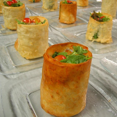 Gourmet Cuisine served vertical phyllo cylinders filled with mixed green salads as appetizers.