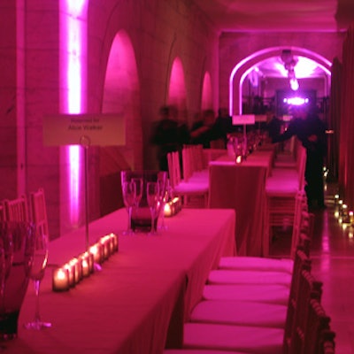 The balcony overlooking Astor Hall featured a long row of high rectangular tables lit in a rosy hue.