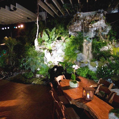 In the jungle section water roiled out of a rocky, leafy waterfall, crafted by Garden State Koi and Aquatic Center, in front of tables made of single thick planks of wood.