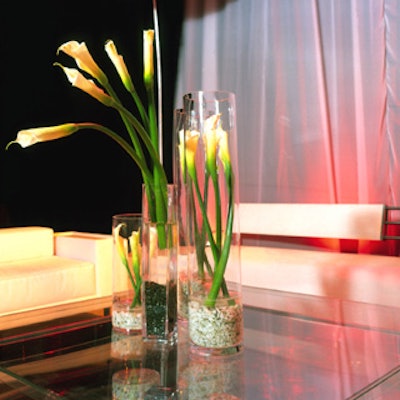 Glass-column vases contained floral arrangements that included calla lilies.