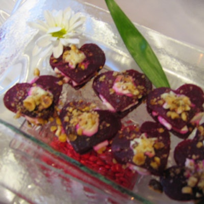 Double-decker heart-shaped beet gorgonzola sandwiches enclosed in square glass containers were displayed on risers of candy hearts.