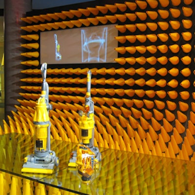 A sheet of Plexiglas resting on cones at the base of a curved backdrop served as a showcase for two Dyson vacuums during Dyson's Canadian media launch at the Design Exchange.