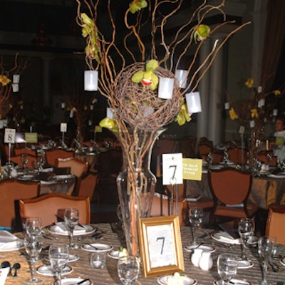 Aragon Group created dining table centerpieces of barren branches, vibrant blooms, and hanging votives.