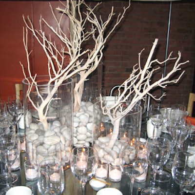 Martin Raffone drew attention to his table with an imposing centerpiece of dead wood branches in large cylindrical beakers filled with large pebbles. This stark look matched the wooden chairs and cabinet in his scenario, and contrasted its metal floor.