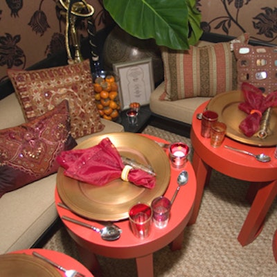 David Easton's design for Lee Jofa's table was reminiscent of a Moroccan tent with a cusped arch entryway, lounge seating, patterned pillows, an ornate mirror, and hookah pipes. Pink, gold, and red colors contrasted the natural hue of the woven mat floor and the banquettes' upholstery.