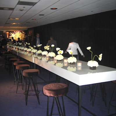 The party area featured white plexiglass communal tables lined with small white flower arrangements and wooden bead tableskirts.