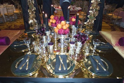 Todd topped the table with a golden mirrored surface and a shimmering concoction of gold and silver flatware, candlesticks, votives, and vases. Colored Swarovski crystals studded dried pomegranates and oranges.