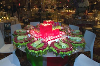 Elizabeth Ryan Floral Design took a modern approach, with two tall rectangular containers filled with red gel and topped with tea lights and complemented by lower, similarly filled containers that held gloriosa lily blossoms and green cymbidium orchids. Clear chargers sat upon rings of red carnations and kermit mums, and the rolled chartreuse napkins were adorned with more lily blossoms.