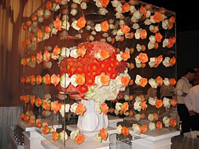 A floral sphere made of daisies, carnations, roses, and hydrangea was the centerpiece of the cocktail reception. The sphere was surrounded by floating orange and white roses suspended inside a custom plexiglass cube.