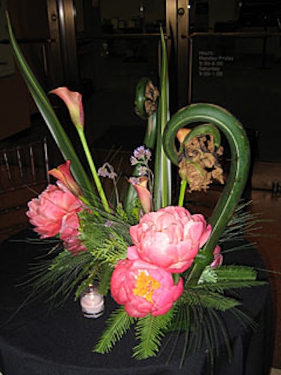 Unusual flower arrangements of pink peonies and giant fiddlehead ferns decorated cocktails tables.