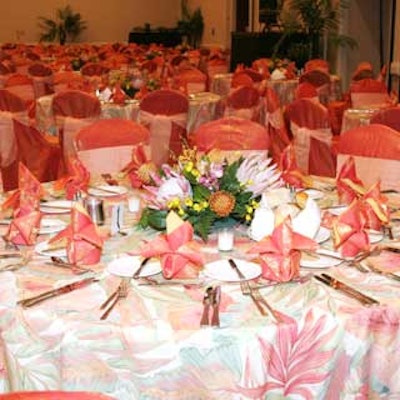 Tables dressed in linens with a tropical floral pattern and topped with exotic floral centerpieces filled the room.
