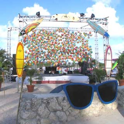 A trussing system outfitted with surfboards was set up in front of a stage with a wall made of beach balls.