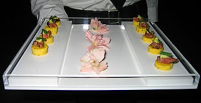 Shiraz NYC passed hors d'oeuvres from trays with two parallel platforms that mimicked the layout of the event space. Pink delphinium flowers lined the center of the trays, representing the accent color chosen for the Loft 21 collection.