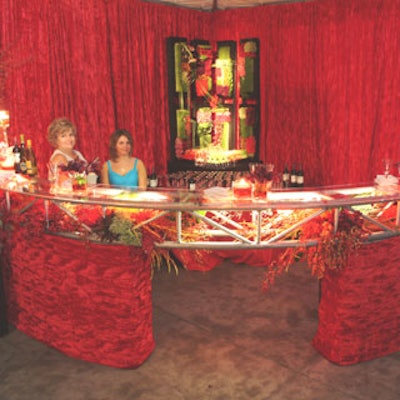 Truss, glass, flowers, and red velvet were used to build a semi-circular bar that was housed within a red velvet draped environment.