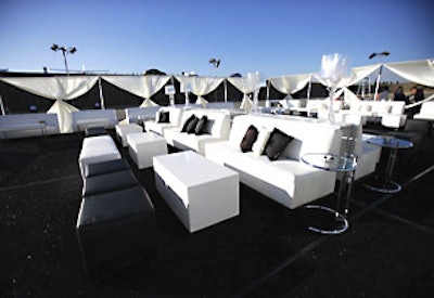 Guests relaxed in an outdoor lounge outfitted with white couches with black and silvery pillows.