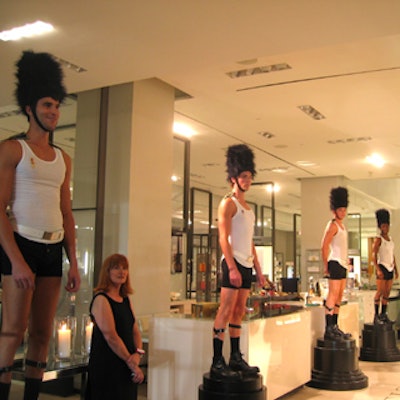 Models from Elite, Ford, and Giovanni posed on black pedestals, wearing only black briefs, white undershirts, and bearskin hats like those worn by British Foot Guards.