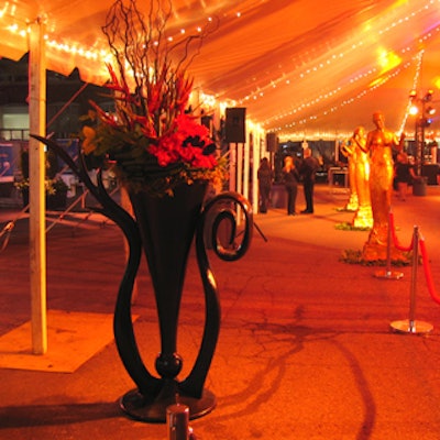 Black Art Deco vases filled with roses, branches, birds of paradise, and feathers decorated the entrance.