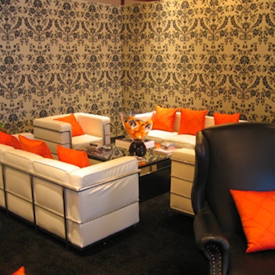The lounge in the photo studio featured classic St. Antoine patterned wallpaper from Farrow & Ball and white leather chairs and couches with orange pillows from Signature Party Rentals.