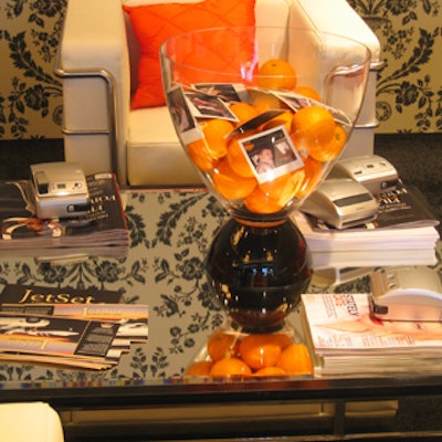 Clear glass vases with black bases contained oranges, and photos of guests taken with Polaroid cameras lingered on the coffee tables.