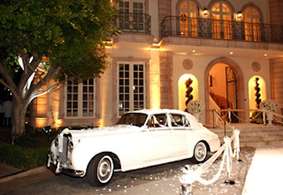 A white Rolls Royce stood sentinel near a receiving line on the white carpet.