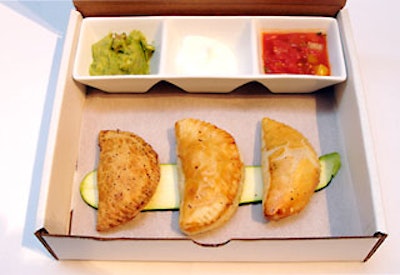 Creative Edge Parties’ first course arrived in a pizza box that listed the dinner menu on the lid and contained three types of empanadas and condiments.