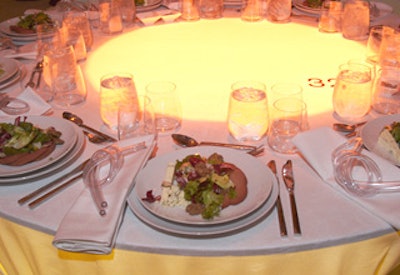 Holland used twisted electrical tubing as “conceptual napkin rings”—the knotted items lay on top of the napkins rather than surrounding the fabric. When guests removed their napkins, they could place the clear plastic forms into the illuminated center of the tables, where they would interact with the light.