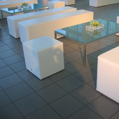 White leather benches and ottomans surrounding frosted-glass coffee tables formed a lounge.