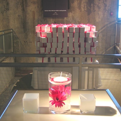 Stacked white gift boxes with pink ribbons and candles floating above pink daisies in water-filled vases decorated the entrance.